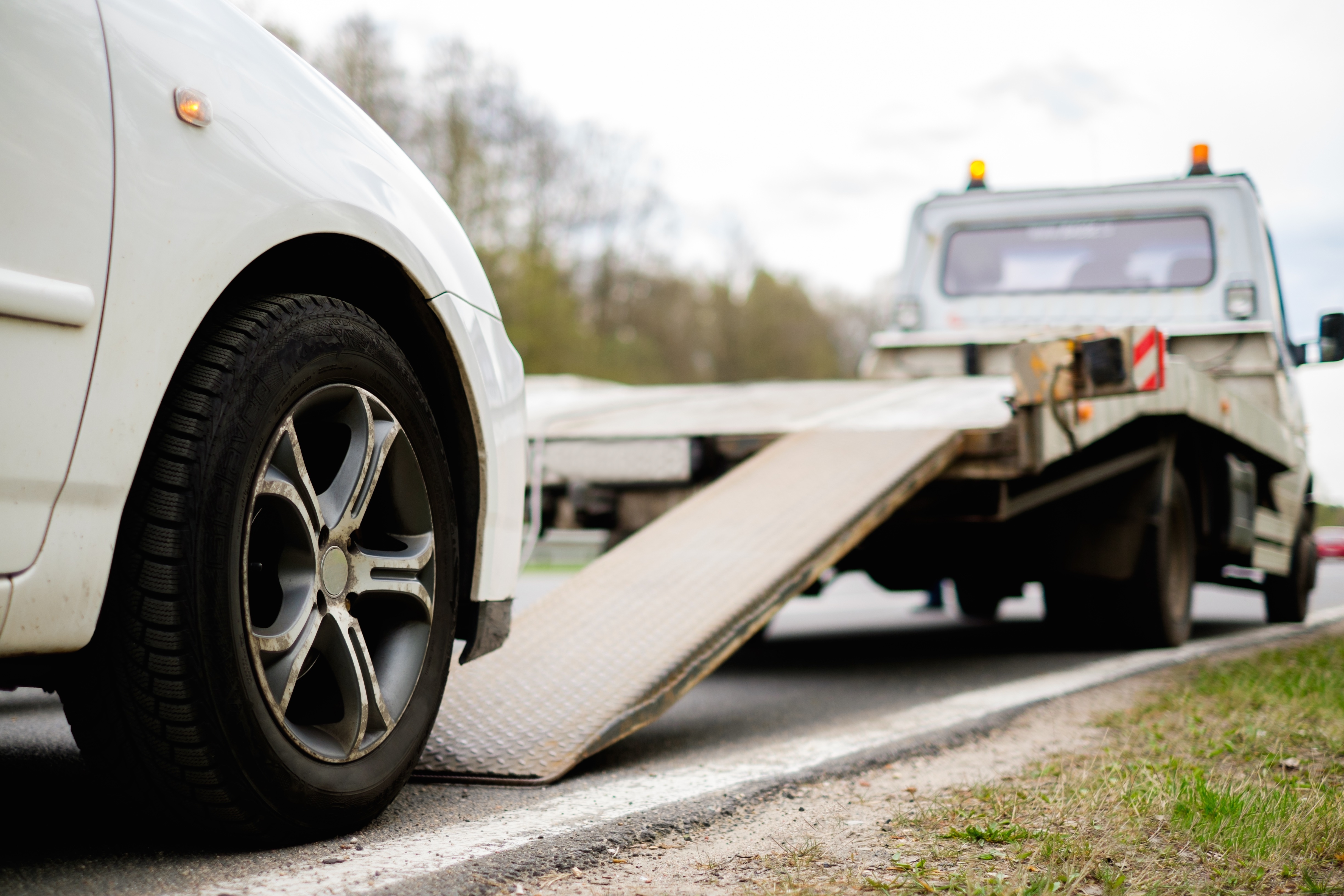 Broken down car about to be towed away by van