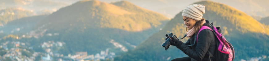 Girl sitting on cliff with camera