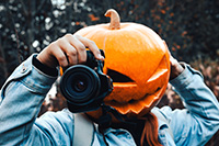 Pumpkin head holding DSLR