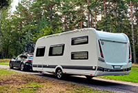 Car towing caravan in forest