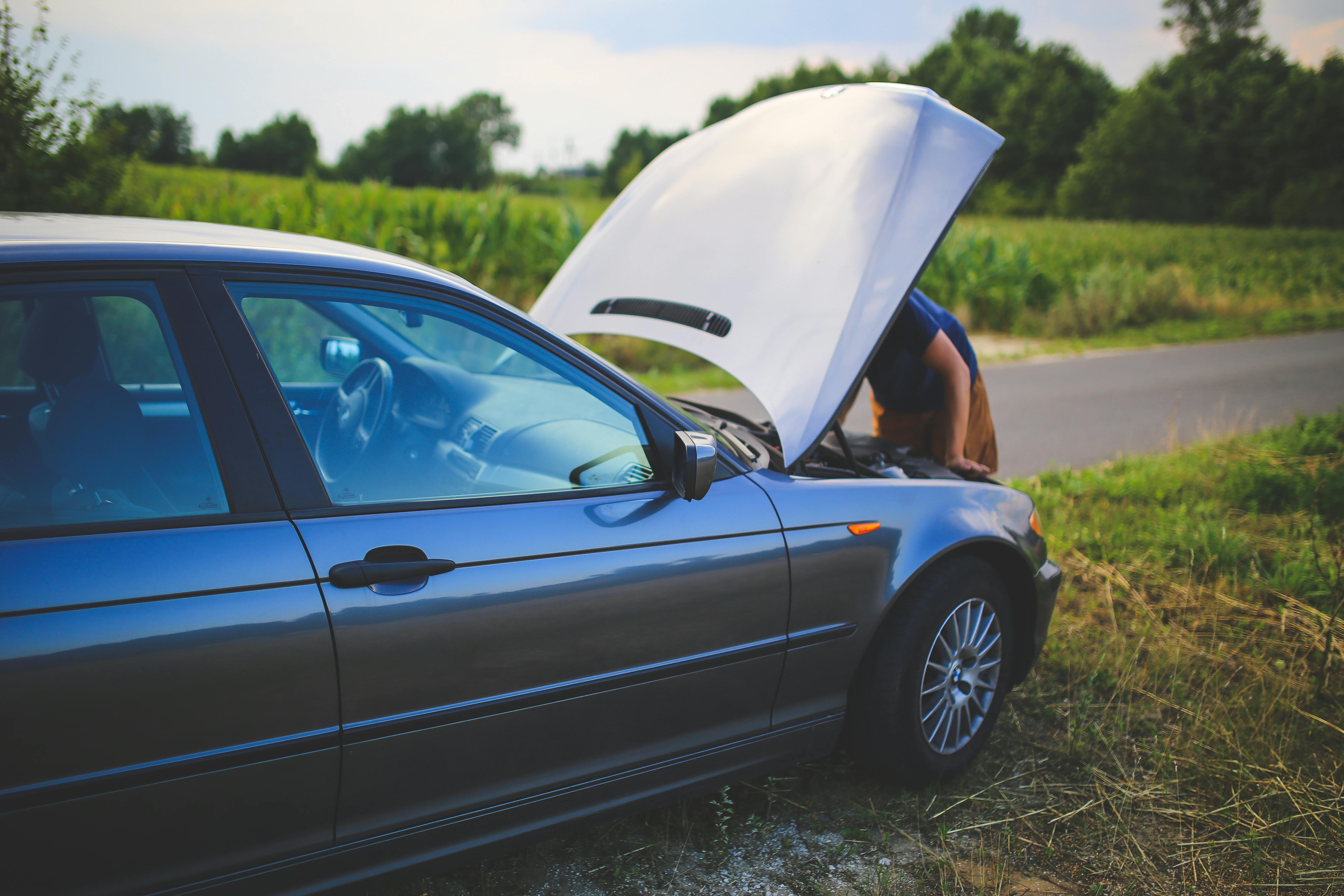 Man looking in car bonnet on the side of the road