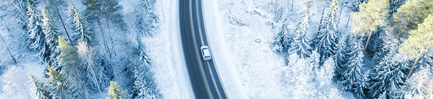 Birds eye view of winding road surrounded by snowy trees